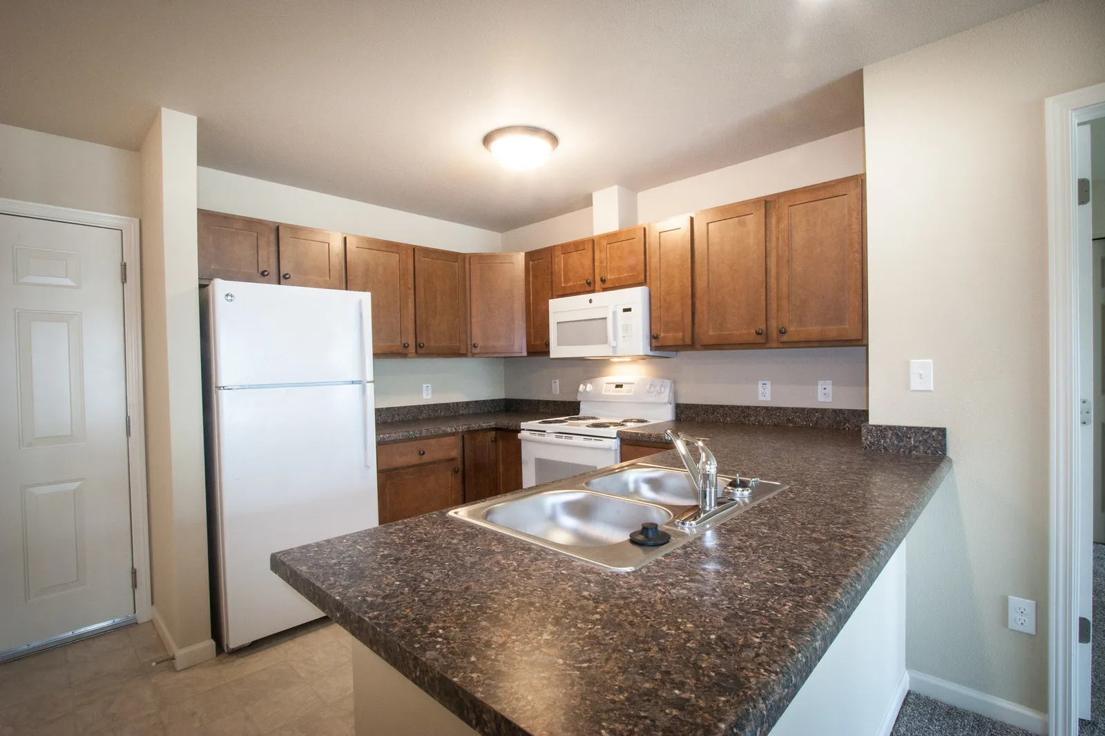 Kitchen with wooden cabinets, white appliances, and granite countertops.