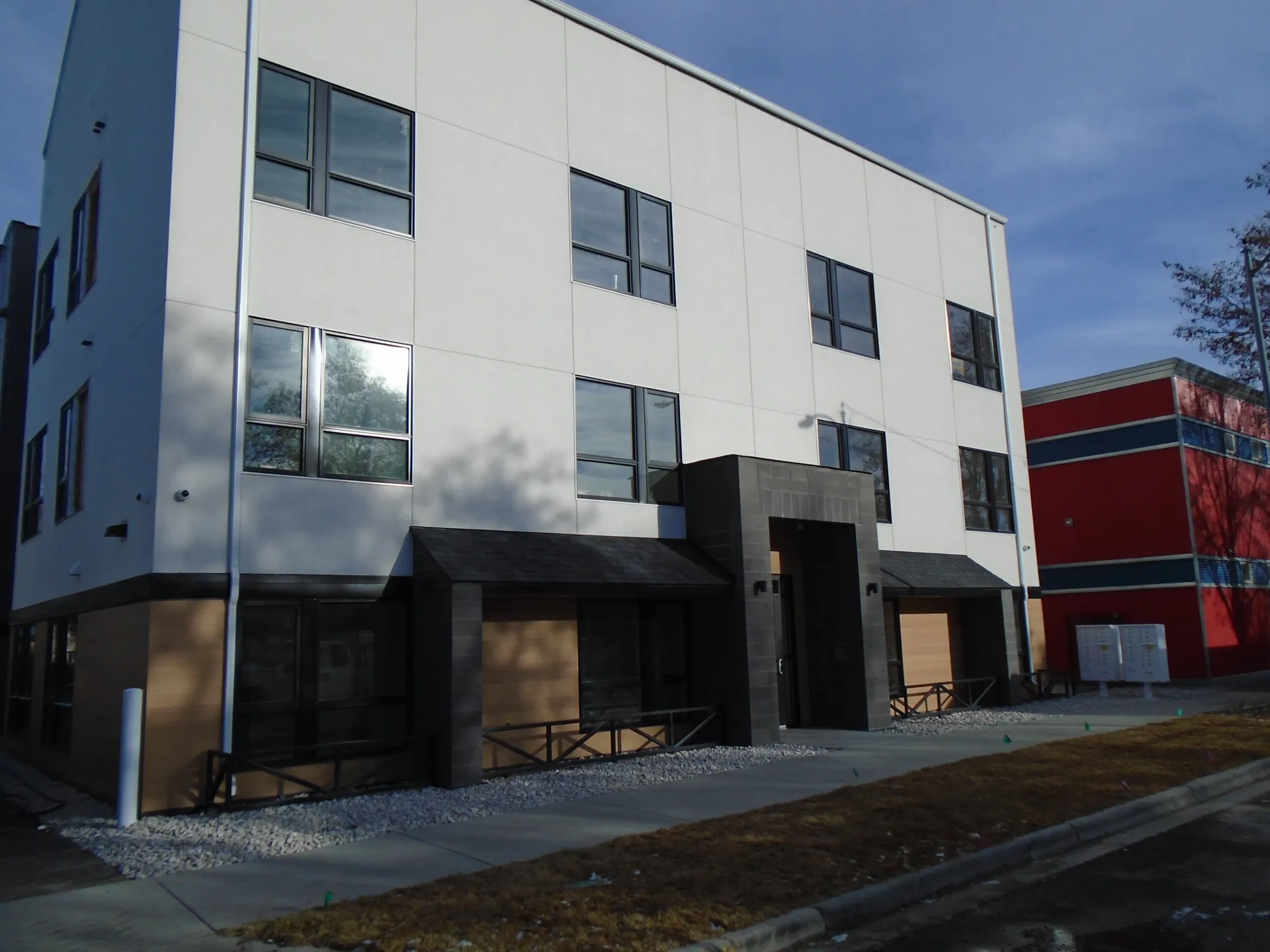 Modern commercial building with white facade, black accents, and large windows.